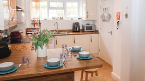 Eine moderne Küche mit weißen Schränken, einer Holz Arbeitsplatte und einem Essbereich mit blauen Tellern und einem Blumenstrauß.