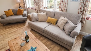 Ein Wohnzimmer mit grauem Sofa, einem Holztisch und einer Weinflasche.