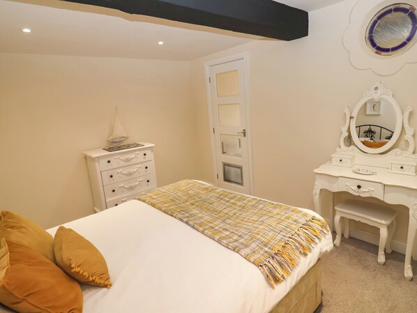 A bedroom with a bed, a dresser, a mirror, and a door.