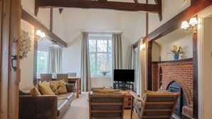 A cozy living room with a fireplace, wooden furniture, and a television. - Maries (Lyme Regis)