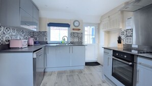 Una cocina moderna con armarios grises, un horno de acero inoxidable y una ventana con vistas al exterior.