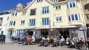 A multi-story building with a cafe on the ground floor. There are outdoor tables and chairs for patrons. - Seahorse (Lyme Regis)