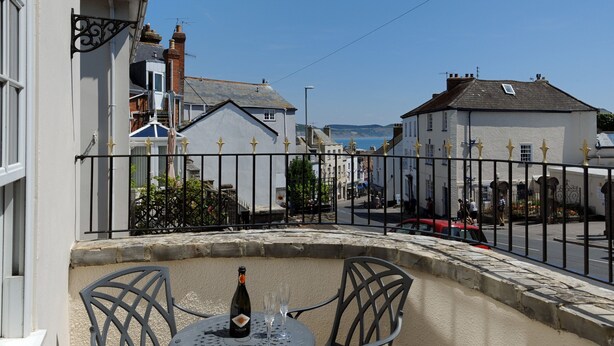 A balcony with a table, a bottle, and two glasses. - Blacksmiths Cottage (Lyme Regis)