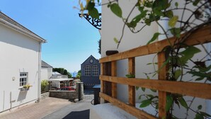 A narrow street with a white building on the left and a blue building with a gabled roof in the background. - Blacksmiths Cottage (Lyme Regis)