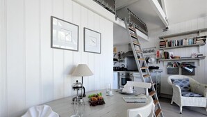 Eine moderne Küche mit weißen Schränken, einer Holzleiter und einem Essbereich mit Tisch für zwei Personen.