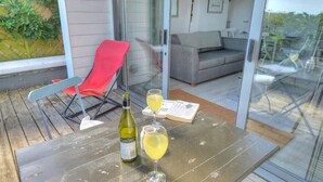 Ein Balkon mit Tisch, einem roten Stuhl, einer Couch und einer Glastür, die in einen Wohnbereich führt.