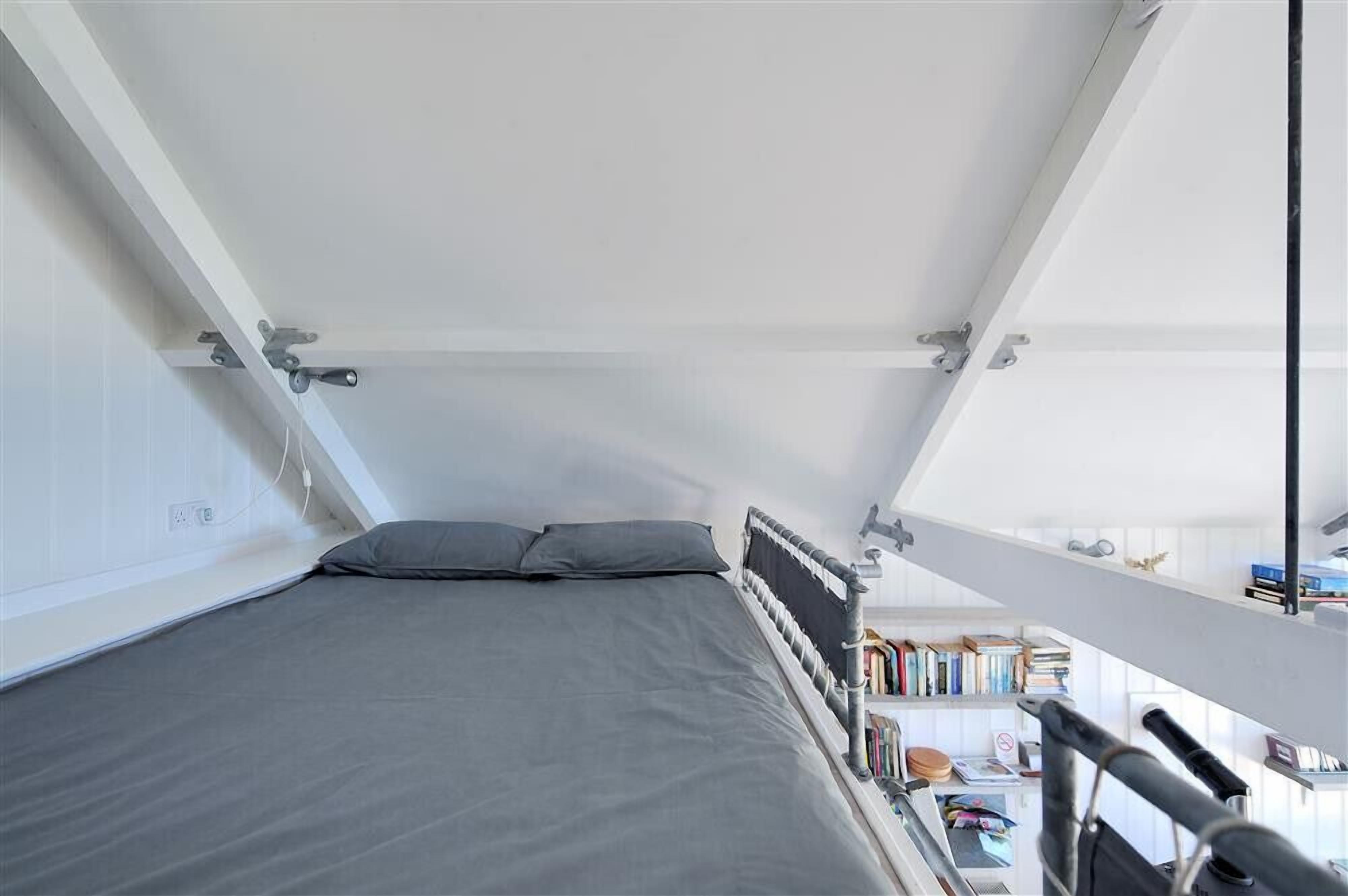 Un dormitorio pequeño y moderno con cama, un escritorio y una estantería.