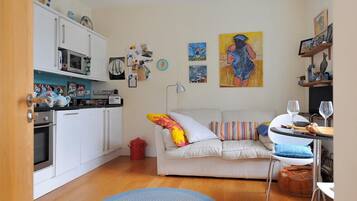 A compact living space with a kitchenette, a sofa, and a dining area.