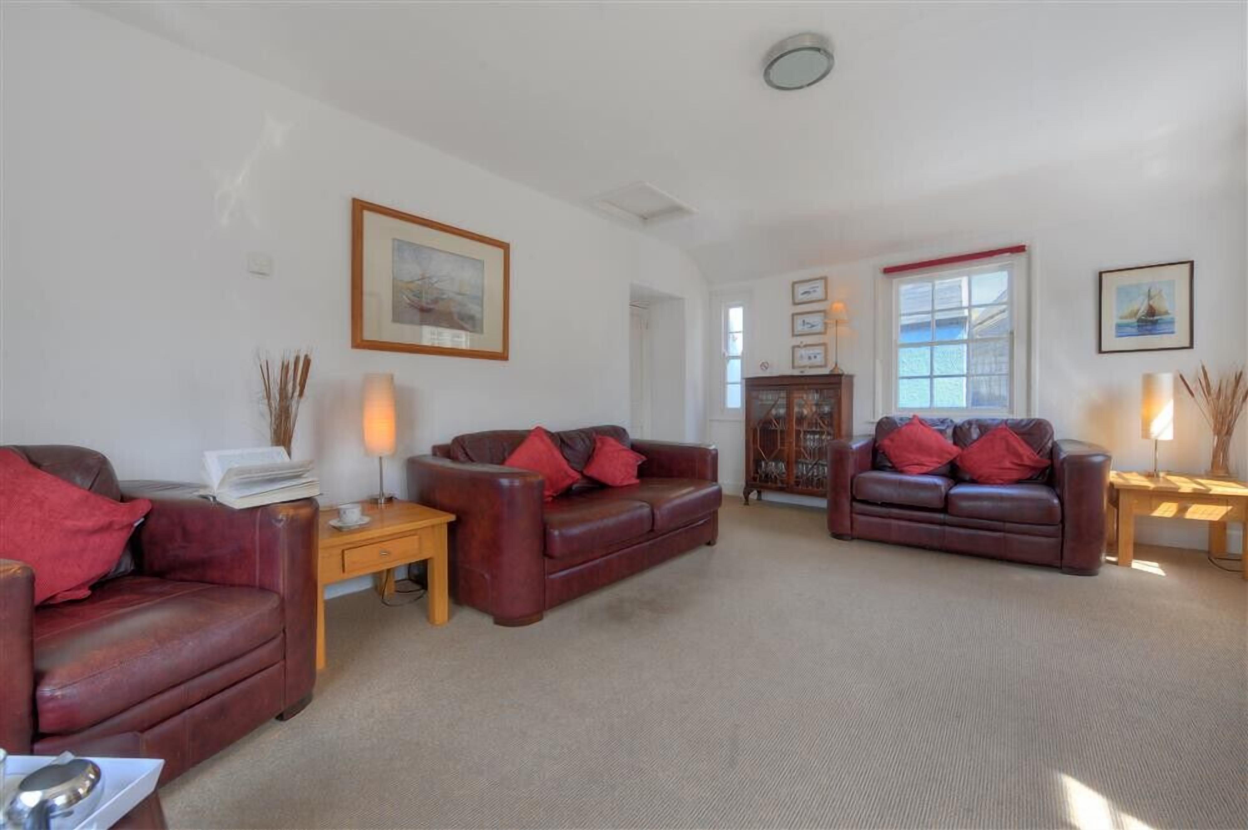 A spacious living room with two leather sofas, a wooden coffee table, and a cabinet.