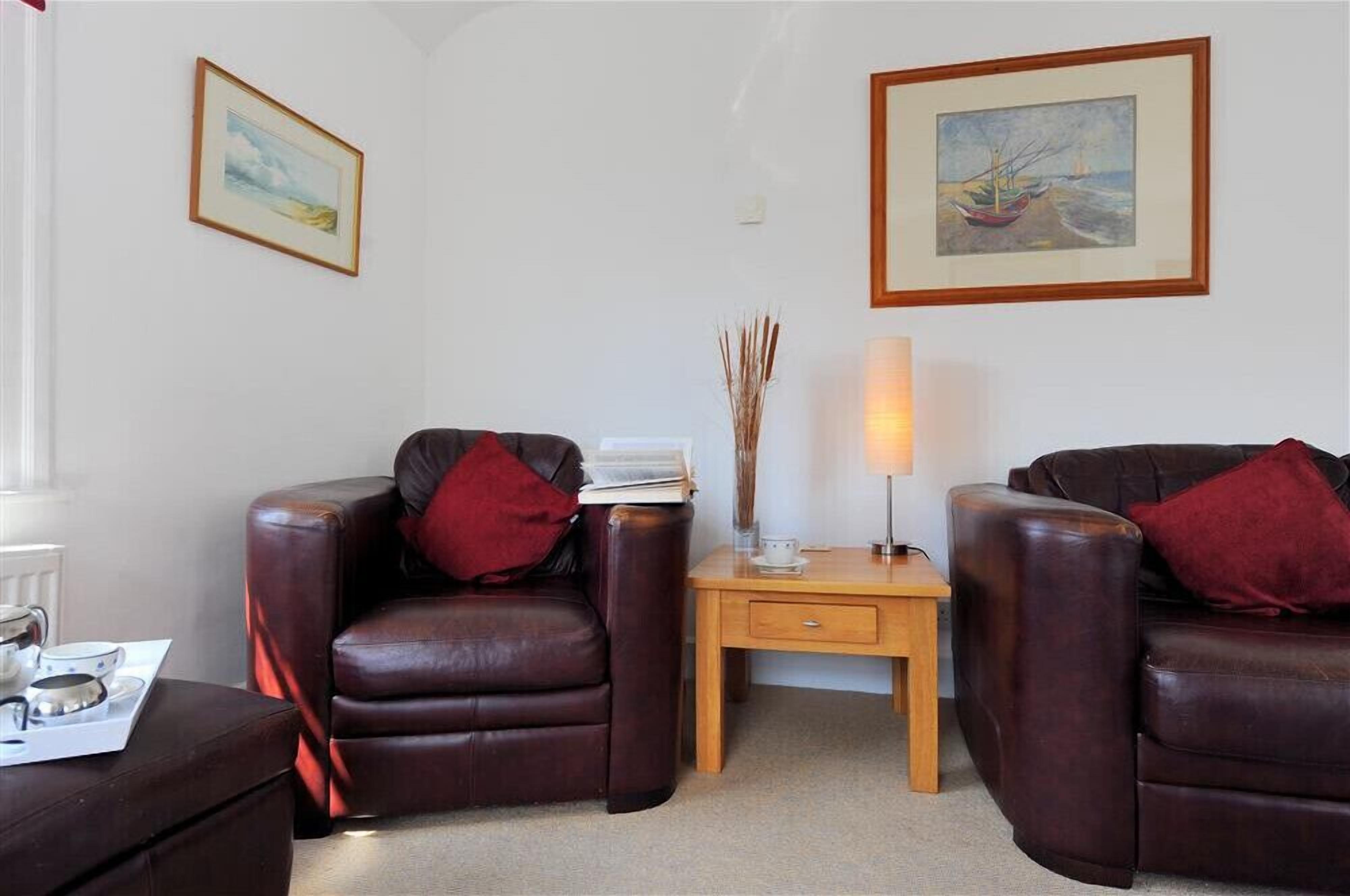 A cozy living room with two leather armchairs, a wooden side table, and a floor lamp.