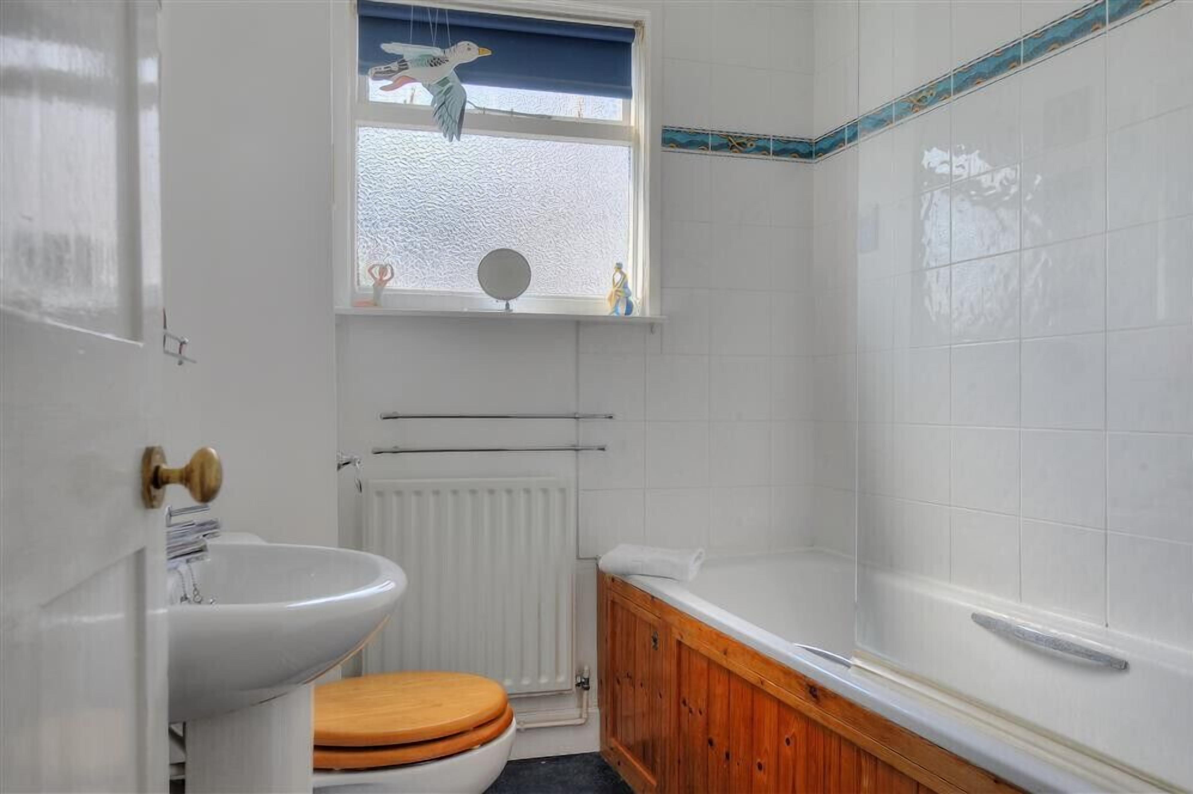 A bathroom with a white sink, wooden toilet, and a bathtub.