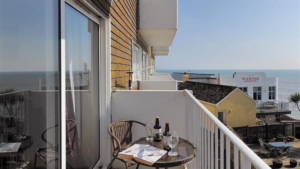 A balcony with a table set for two, overlooking the sea. - 4 Bay View Court (Lyme Regis)