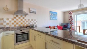 A modern kitchen with a built-in oven, a stainless steel range hood, and a checkered backsplash. - 4 Bay View Court (Lyme Regis)