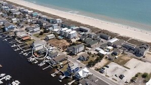 Ett flygbildsfoto av ett bostadsområde vid kusten med hus, en småbåtshamn och en strand.