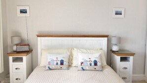 Une chambre à coucher avec un lit, deux tables de chevet et deux lampes.