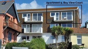 Un immeuble résidentiel à plusieurs étages, doté de balcons et d’une cour offrant une vue sur la baie.