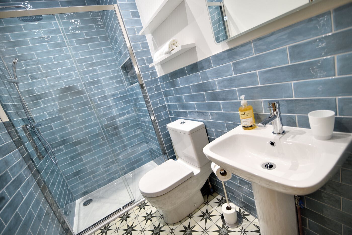 A bathroom with a glass-enclosed shower, a toilet, a sink, and a mirror.