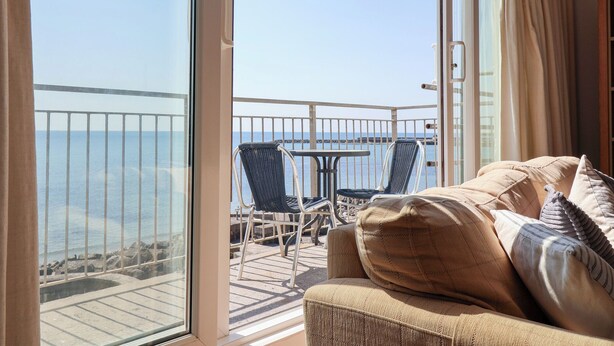Un balcon avec vue sur la mer, une table et deux chaises.