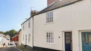A narrow street with white buildings, a blue door, and a number '12' sign. - 3 Dolphin Cottages (Lyme Regis)