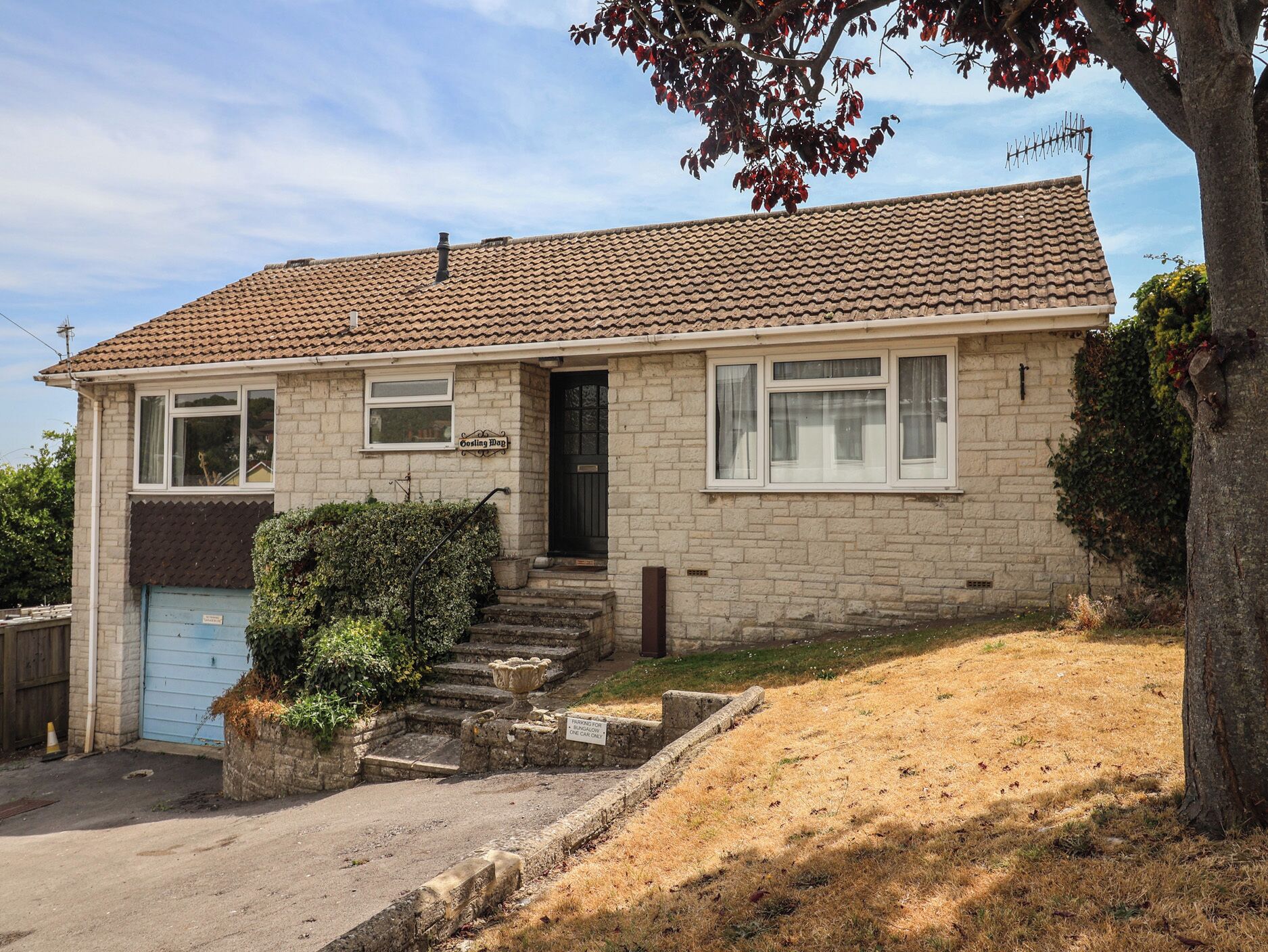 A two-story house with a tiled roof, a front door, and a garage.