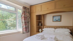 Quarto de hotel com cama, janela com cortinas, um armário de madeira e um quadro na parede.