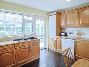 Une cuisine avec des meubles de rangement en bois, un évier, une cuisinière, un grille-pain et un lave-vaisselle.