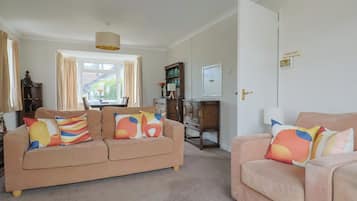 A living room with two sofas, a dining table, and a kitchen area.