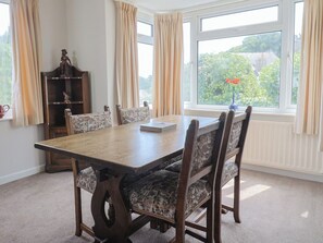 Une salle à manger avec une table en bois et des chaises à motifs, un buffet en bois et une fenêtre avec des rideaux.