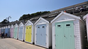 A row of colorful beach huts with white exteriors and pastel-colored doors. - Granny's Teeth (Lyme Regis)