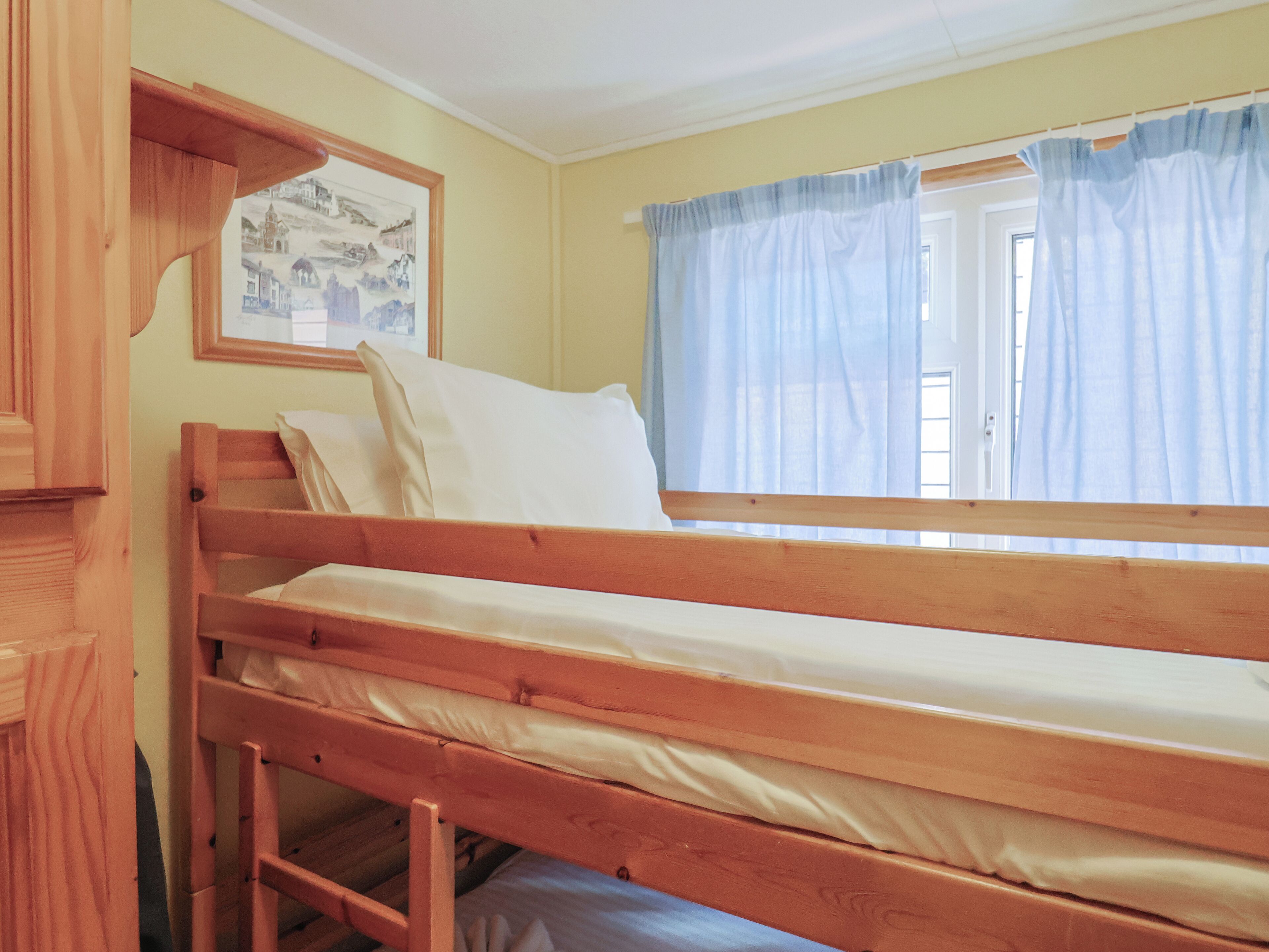 A bunk bed in a room with a window and a framed picture on the wall.