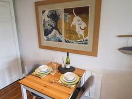 Una mesa de comedor con una obra enmarcada encima, una botella de vino y una copa sobre la mesa.