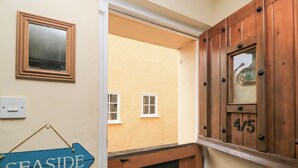 A hallway with a wooden door, a mirror, and a sign indicating 'SEASIDE'. - 4/5 Georges Square (Lyme Regis)