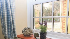 A window with a view of a garden, a stone, and a potted plant on the window sill. - 4/5 Georges Square (Lyme Regis)