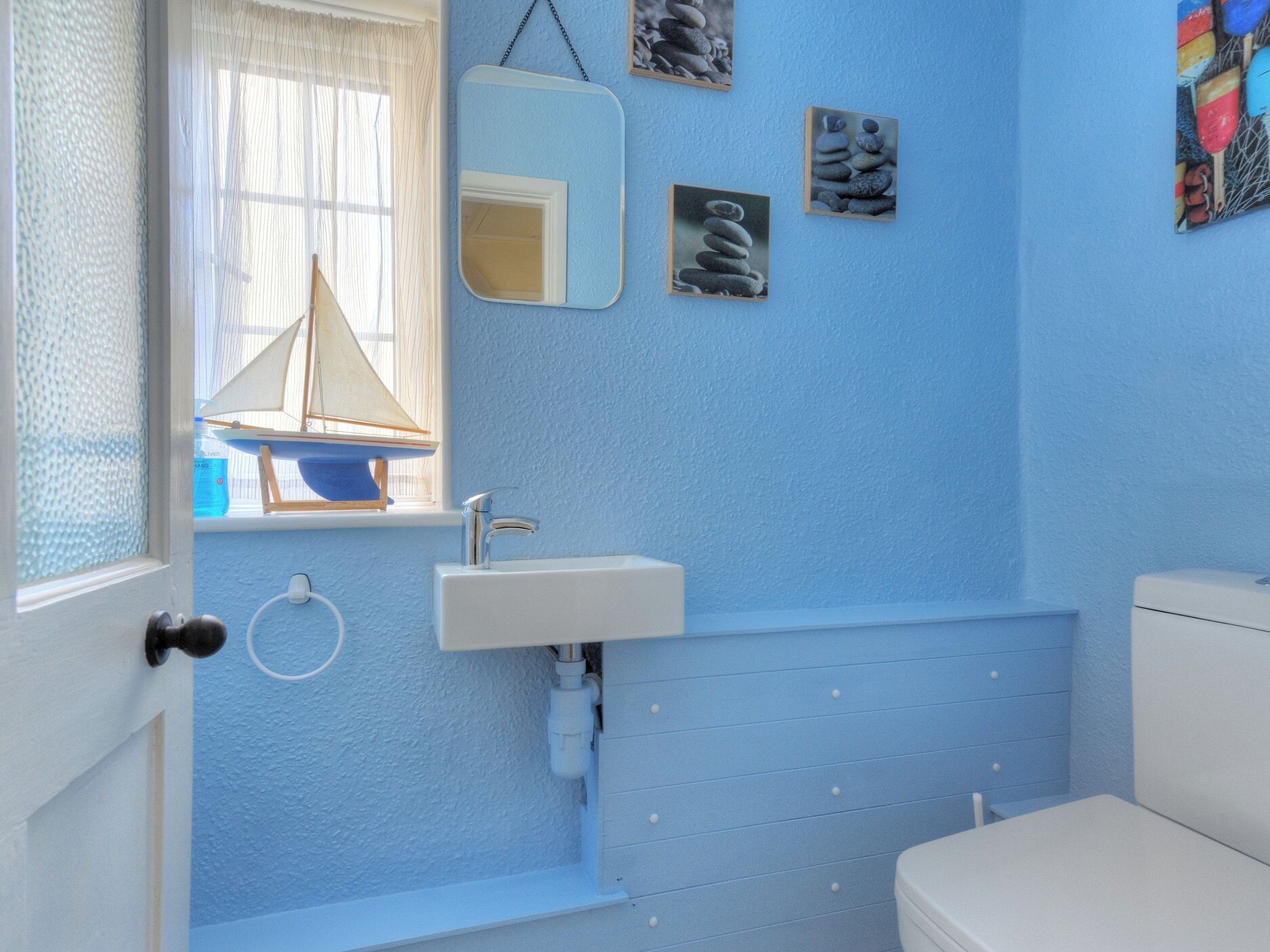 Une salle de bain avec un mur bleu, un lavabo blanc, un miroir et des toilettes.
