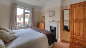 Une chambre à coucher avec un lit, une commode, un miroir et une cheminée.