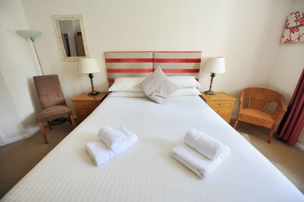 A hotel room with a large bed, two nightstands, a chair, a lamp, and a mirror.