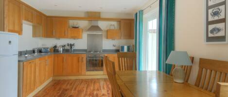 A compact kitchen with wooden cabinets, a dining table, and a stove.