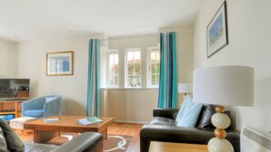 A living room with a sofa, a coffee table, a TV, and a bookshelf. - 8 Buckfields (Lyme Regis)