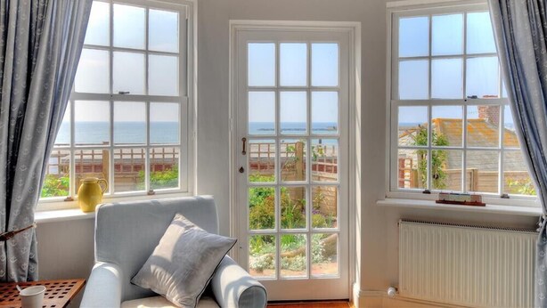 A room with a view of the sea, a sofa, a radiator, and curtains. - Ross House (Lyme Regis)