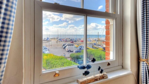 A window with a view of a parking lot and a clear sky. - 2 Cobb View (Lyme Regis)