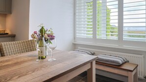 Un comedor con una mesa de madera, dos copas de vino y una botella.