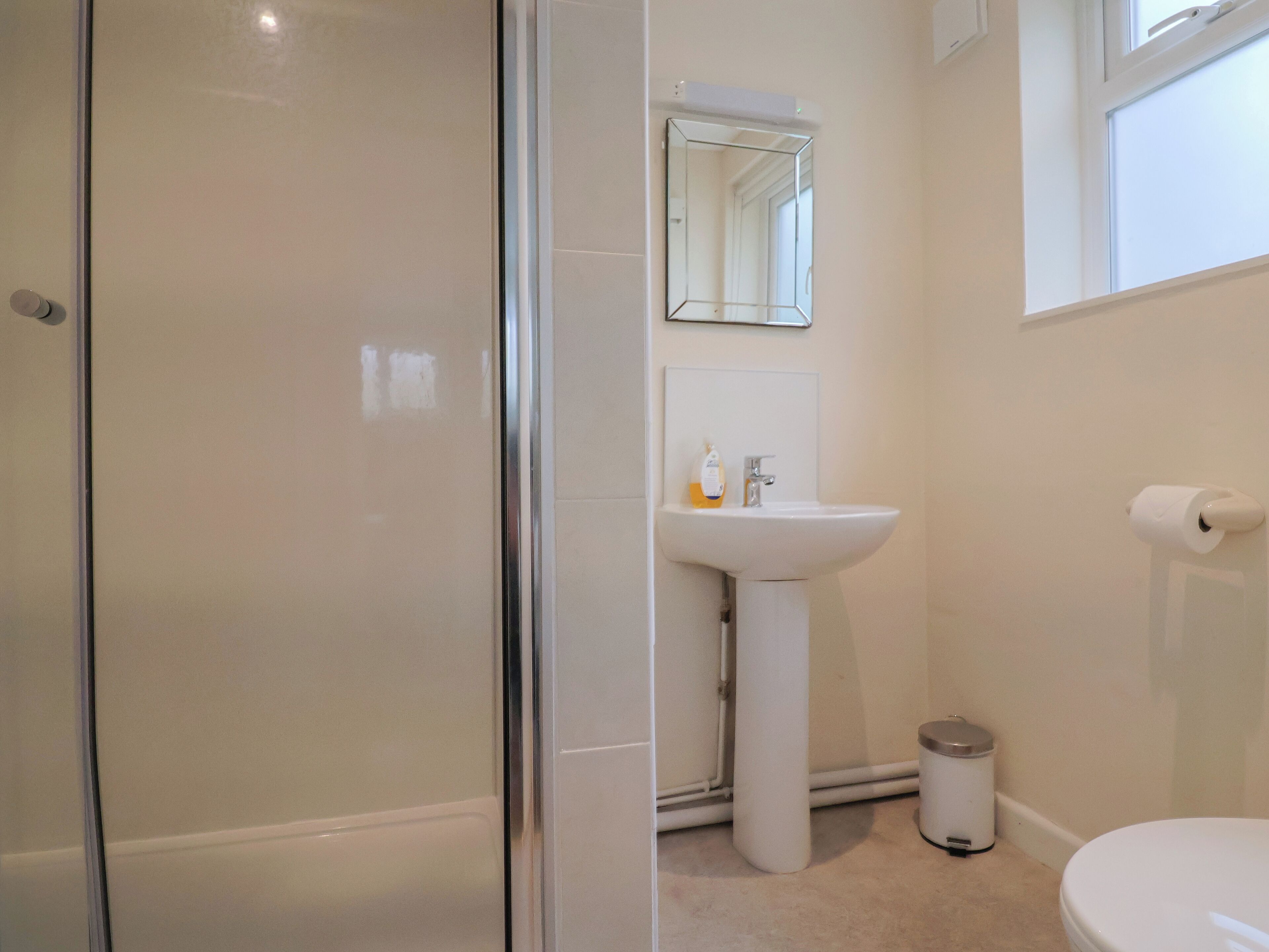 Un bagno con box doccia in vetro, lavabo con specchio sopra e un water.