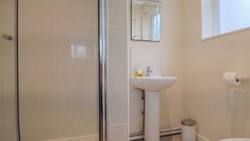 Un bagno con box doccia in vetro, lavabo con specchio sopra e un water.