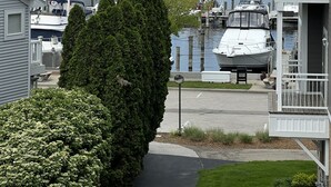 Uma marina com barcos atracados, um edifício grande com a inscrição 'KEENAN MARINA' e um prédio residencial com varanda.
