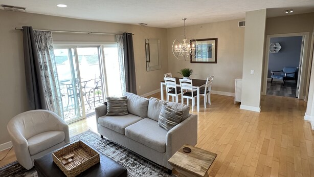 Uma sala de estar ampla com sofá, poltronas, mesa de centro e área de jantar com cadeiras e mesa.