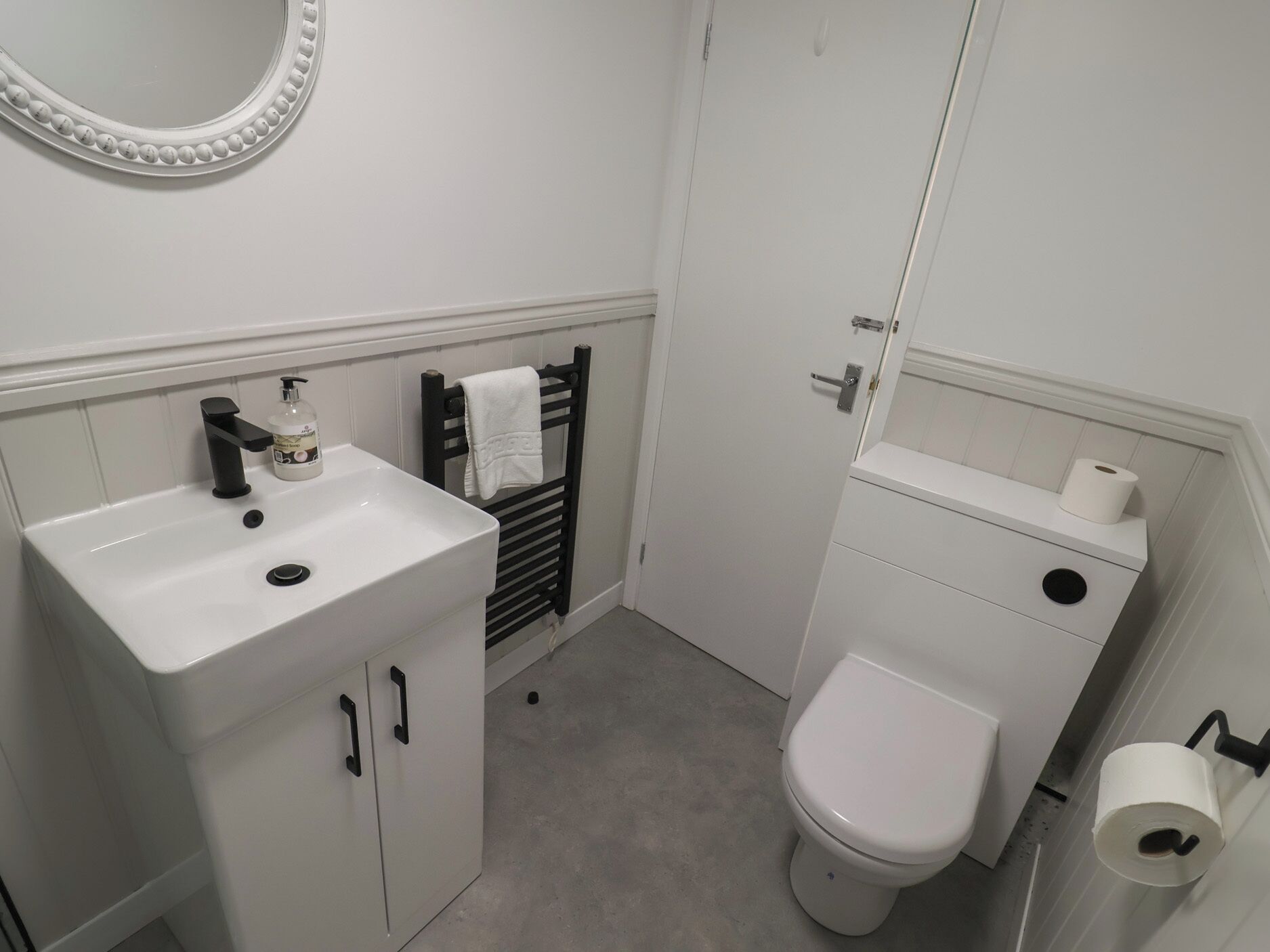 Un baño con lavamanos, inodoro y toallero blancos.