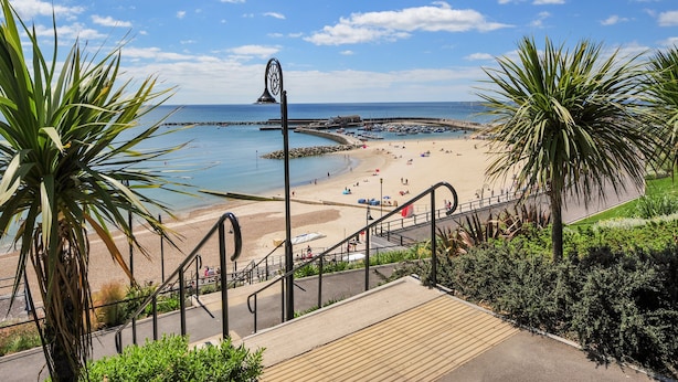 Une vue côtière comprenant une plage, une jetée et un escalier descendant vers la plage.