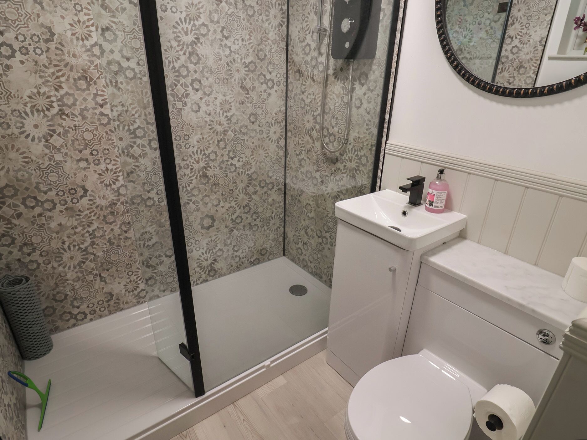 Un baño con ducha, inodoro, lavamanos y espejo.