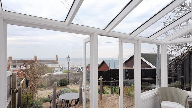 A conservatory with a view of a garden and neighboring houses.