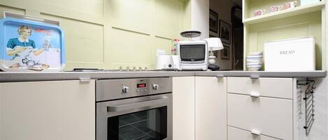 Una cocina con microondas, horno y cafetera en la encimera.
